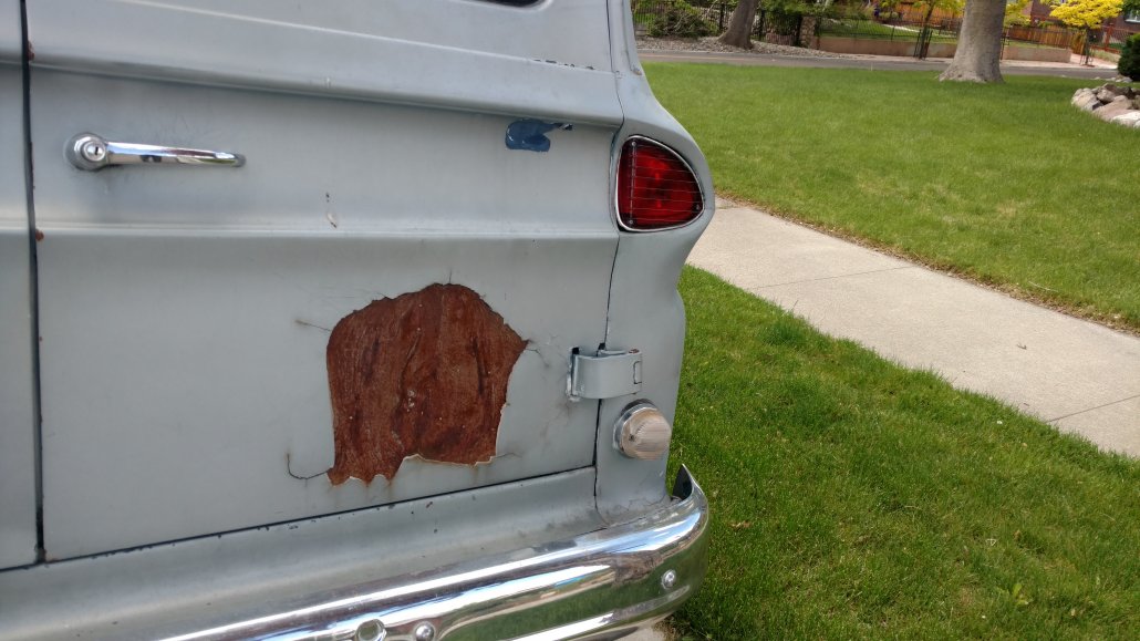 A photo of the back of a truck where part of the paint is chipping away and looks, with imagination, like a bear